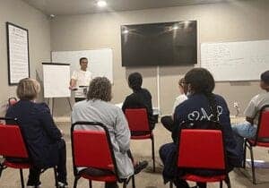 men and women seated in a group session as part of a meth addiction rehab program