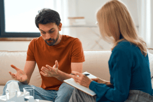 Two people sitting on a couch and talking about the benefits of anxiety treatment