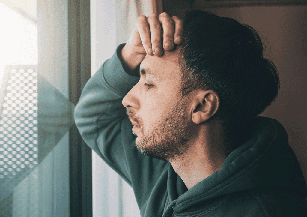 Man looking out window and wondering, "Are benzodiazepines physically addictive?"
